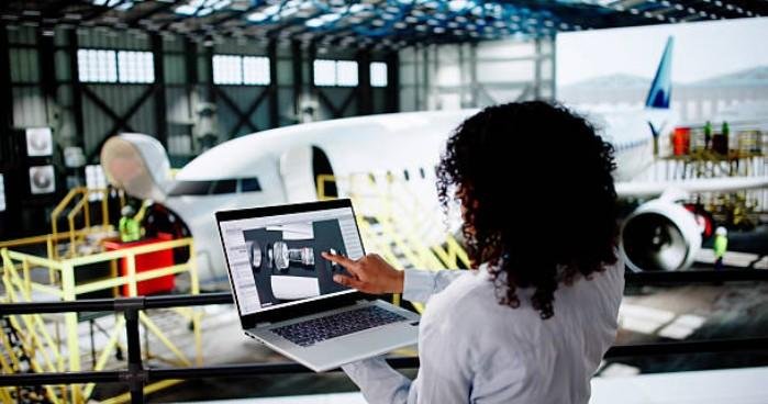 A professional using a laptop to review digital schematics in an aircraft hangar, symbolizing the technical planning and infrastructure phase of how to set up a business network.