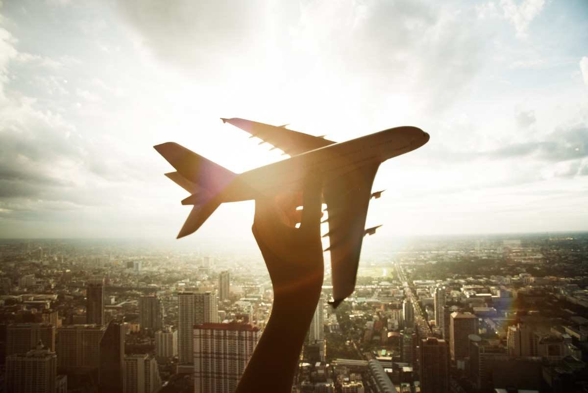 A silhouette of a hand holding a model airplane against a sunlit skyline, visualizing the journey of how to get aviation maintenance repair license