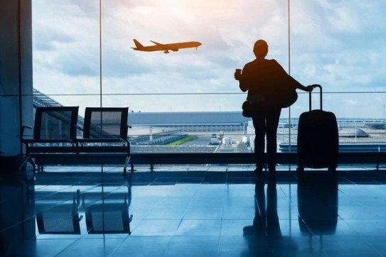 A traveler watches a plane take off at the airport, pondering, Can I take food through airport security while waiting for their flight.